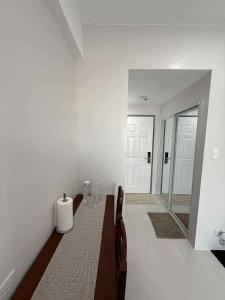 Una habitación blanca con una cama y un espejo. en Bayani Hall - Studio Condo Unit, en Dagupán
