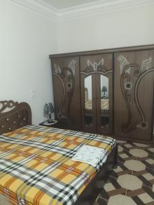 una camera da letto con un letto con testiera in legno di appartement Tozeur médina a Tozeur