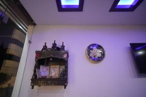 a clock on the side of a wall next to a shelf at The Holy Stay in Haridwār