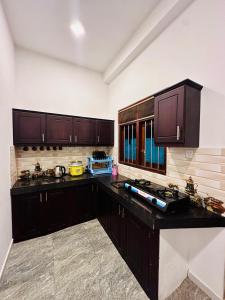 a kitchen with wooden cabinets and black counter tops at Abheena - Weligama in Weligama