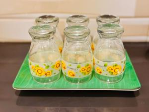 a tray with four glass bottles with yellow flowers on them at Abheena - Weligama in Weligama