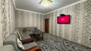 a living room with a couch and a tv on the wall at MOK Apartment in Samarkand