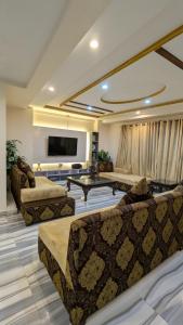 a living room with couches and a flat screen tv at Cozy Family Apartment in Murree in Murree