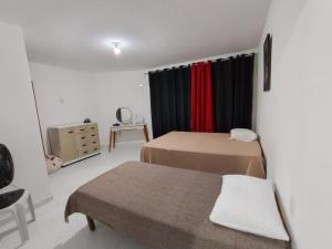 een kleine kamer met twee bedden en een raam bij House 31 Pipa in Pipa