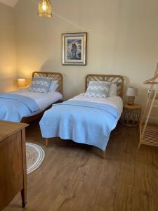 a room with two beds with blue sheets in it at High Shilford Barn in Ridingmill