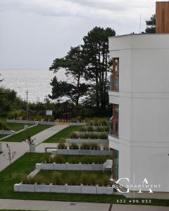 a white building with a garden in front of the water at Gold Apartment E54 Let's Sea Baltic Park Gąski in Gąski +104 photos