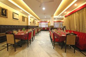 un comedor con mesas y sillas rojas en Le Grand Hotel, en Haridwar