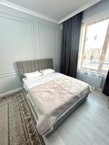 a bed in a bedroom with a large window at Keruen Saray Apartaments 1 in Türkistan