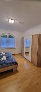 a bedroom with a bed and two windows and a wooden floor at Charmante, ruhige Erdgeschosswohnung mit Balkon in Lüdenscheid