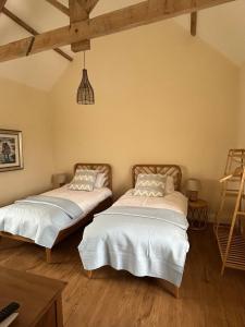 two beds in a room with wooden floors at High Shilford Barn in Ridingmill