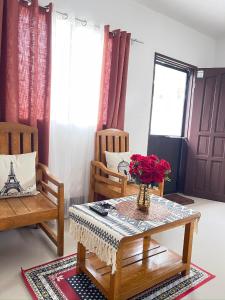 a living room with two chairs and a table with a vase of flowers at J&L Apartment 
