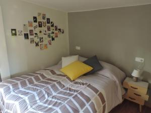 a bedroom with a bed with a yellow pillow and pictures on the wall at Casa La Muralla, reformada en Casco Antiguo in Cuenca