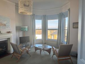 Una sala de estar con una mesa y sillas y un televisor. en Sea views at Carina centrally located in village, en Seaview