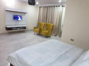 a bedroom with a bed and two chairs and a television at Peters 3 Bedrooms Duplex Service Apartment in Lekki +5 photos