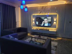 a living room with a television with a man talking on a cell phone at Peters 3 Bedrooms Duplex Service Apartment in Lekki