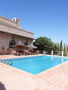 a swimming pool with chairs and umbrellas next to a building at Maison la chèvre By Nath & Lulu in Essaouira