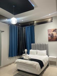 a bedroom with a large bed with blue curtains at Golden View Boutique Guesthouse in Windhoek