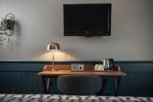 a desk with a chair and a television on a wall at Home Hotel Kompaniet in Nyköping