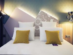 a bed with white pillows and a headboard at Hôtel Mercure Thionville Centre Porte du Luxembourg in Thionville