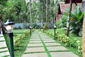 un chemin de pierre avec des lumières dans un jardin dans l'établissement Snow White Wayanad Premium Pool Resort, à Wayanad