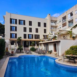 a hotel with a swimming pool in front of a building at Mamboo Hotel Cala Ratjada in Cala Ratjada