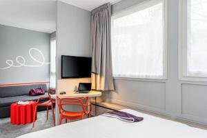 a bedroom with a bed and a desk and a tv at ibis Styles Paris Velizy in Vélizy-Villacoublay