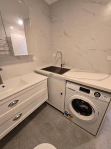 The Greenview Luxe Home - Hornsby في هورنسبي: مطبخ أبيض مع مغسلة وغسالة ملابس