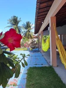 a patio with a red flower and a hammock at Sitio Damiana in Paracuru +14 photos