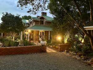 a large house with a brick wall and lights at Glen Eden Lodge in Lidgetton
