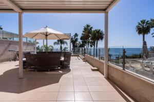 d'une terrasse avec un parasol, des chaises et l'océan. dans l'établissement Beachfront Luxury Living Limassol, à Limassol