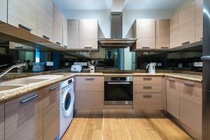 une cuisine avec des armoires en bois et une laveuse et une sécheuse dans l'établissement Beachfront Luxury Living Limassol, à Limassol