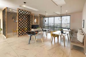 een woonkamer met tafels, stoelen en ramen bij City Express Plus by Marriott Ciudad de México Mundo E in Mexico-Stad