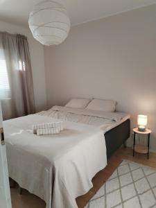ein weißes Schlafzimmer mit einem großen Bett und einer Lampe in der Unterkunft Valoisa saunallinen luhtitalokaksio Joupista in Seinäjoki