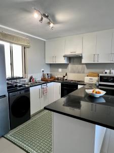 a kitchen with white cabinets and a bowl of fruit on a counter at SaltySky Penthouse in Gansbaai +4 photos