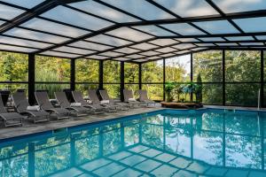 an indoor pool with chairs and a large room with windows at Domaine de la Résidence - Hôtel, Spa & Restaurant in Moulins-lès-Metz