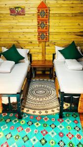 Habitación con 2 camas, mesa y alfombra. en Amoy River Lodge, en Moshi