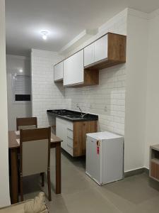 een keuken met witte kasten, een tafel en een koelkast bij Edifício Catarina in Sorocaba
