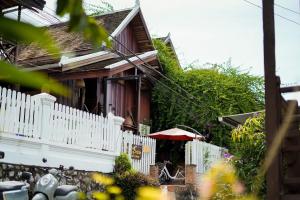 a house with a white fence and an umbrella at Sarana Guest House in Luang Prabang