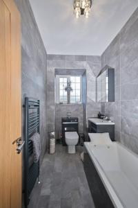 a bathroom with a tub and a toilet and a sink at Village Stay in The Heart of Torrance in Glasgow