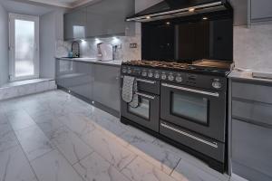 a kitchen with a stove and a counter top at Village Stay in The Heart of Torrance in Glasgow +7 photos