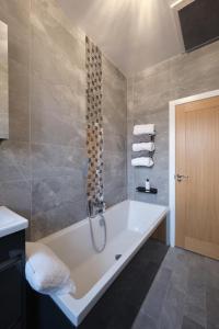 a bathroom with a bath tub with a shower at Village Stay in The Heart of Torrance in Glasgow