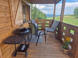 a porch of a cabin with chairs and a grill at Leśna Chatka Kotlina Kłodzka in Kłodzko +13 photos