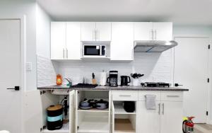 a white kitchen with white cabinets and a microwave at Kelvista's suite in Winnipeg