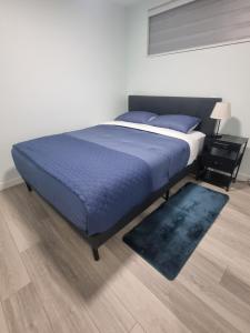 Un dormitorio con una cama con sábanas azules y una alfombra. en Kelvista's suite, en Winnipeg
