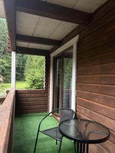 een tafel en stoelen op de veranda van een huis bij Гірська роса 2 in Synevyrsʼka Polyana +1 foto