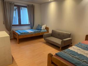a bedroom with a couch and a chair and a window at Fachwerkzauber Eggenbach in Ebensfeld