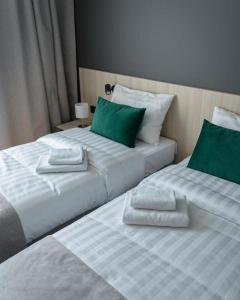 two beds with green and white pillows in a room at Paradise Otel 
