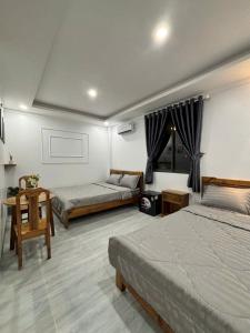 a bedroom with two beds and a table and a chair at Khách Sạn Hải Châu in Ba Ria
