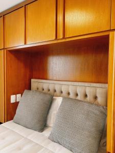 Bett mit einem Kopfteil aus Holz und 2 Kissen in der Unterkunft Apartamento Serra Bella Itaipava in Araras Petropolis + 4 Fotos