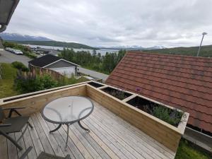 eine Holzterrasse mit einem Tisch und einem Stuhl darauf in der Unterkunft Apartment, Sea View, Terrace, Free Parking in Tromsø